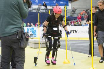 A girl with mobility problems manages to walk with the help of walking equipment and crutches and experts monitor her steps